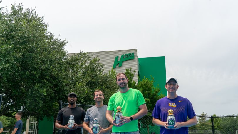 Several HCSS employees pose outside with trophies