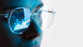 A person wearing glasses with data in the reflection.